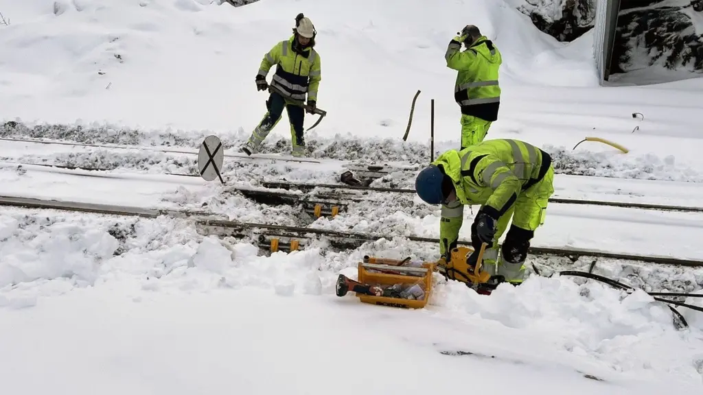 Banarbetare sitter i snön och lagar järnvägen i Vassijaure