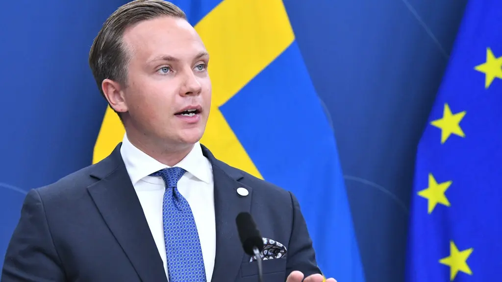 Man med bakåtslickat hår gestikulerar vid en presskonferens. 