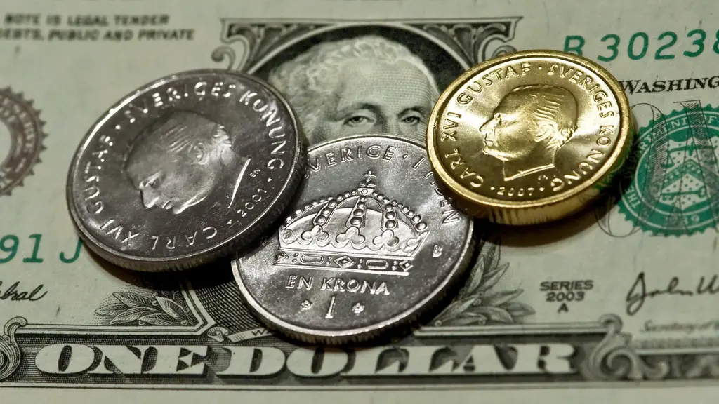 Svenska mynt ligger ovanpå en amerikansk dollarsedel. 