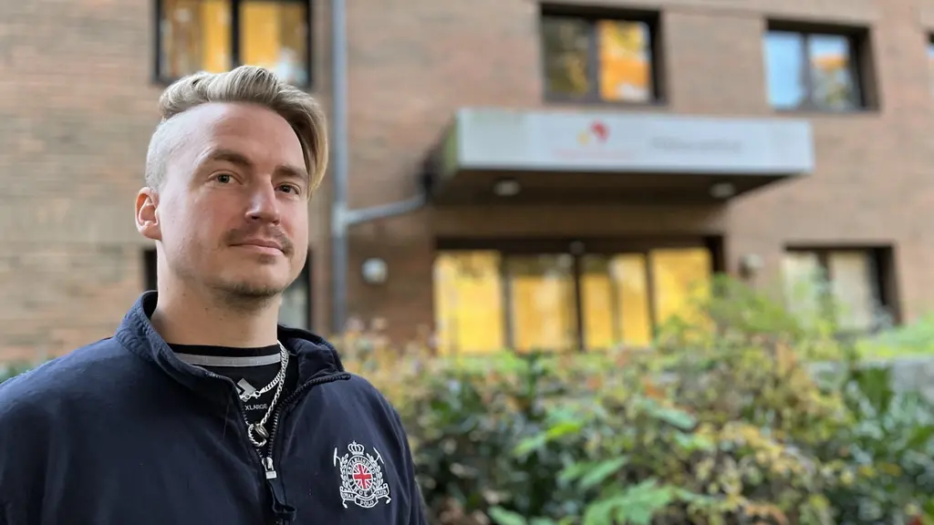 En man framför en tegelbyggnad.