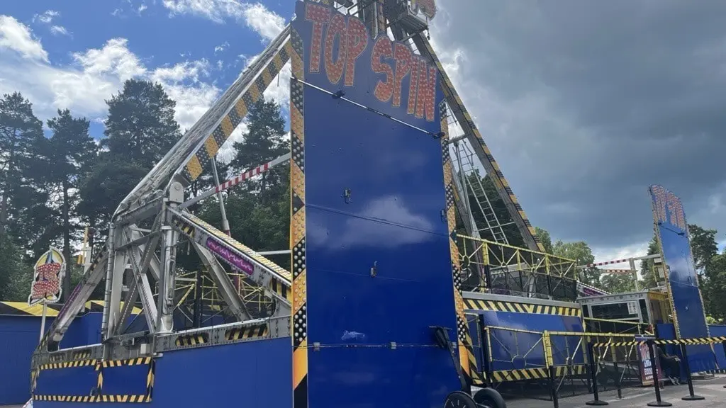 Top Spin på Parken Zoo avspärrad med polisband efter olycka där en kvinna skadats. Den stora nöjesattraktionen står stilla under mörka moln.