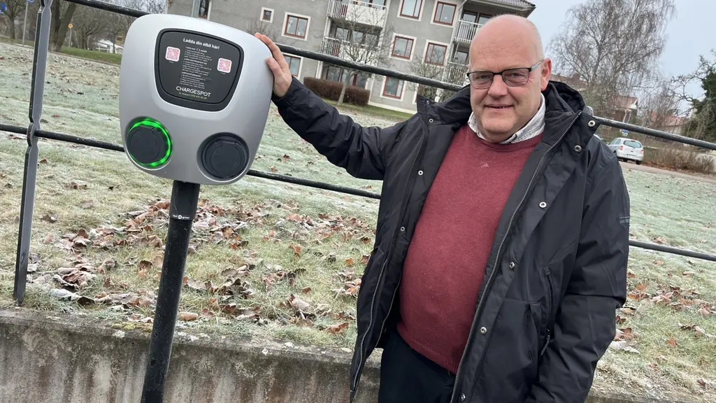 Niklas Johansson, vd för Tranås Energi, står utomhus vid en elbilsladdare i en frostig miljö med flerbostadshus i bakgrunden.
