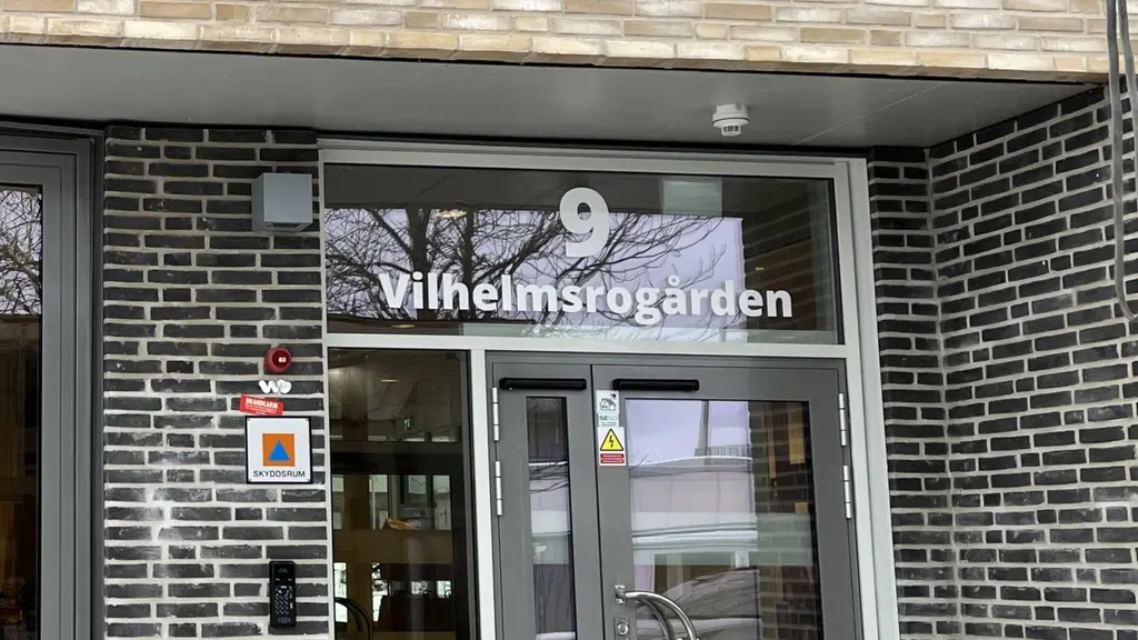 Bild på en dörr in till Vilhelmsrogården. Delar av fasaden till huset syns som är i mörkt tegel.