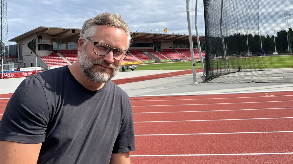 Johan Engberg, en av arrangörerna för SM i friidrott i Karlstad och Kil samt IF Götas klubbchef, sitter vid en friidrottsarena med löparbanor och läktare i bakgrunden.