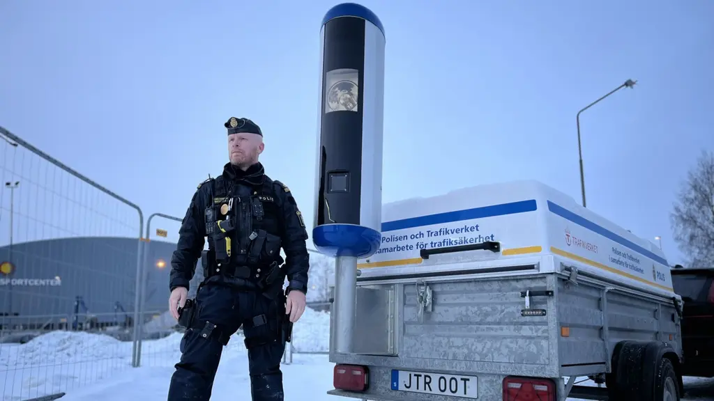 Trafikpolis Petter Magnusson står framför en mobil fartkamera som är monterad på en släpvagn. 