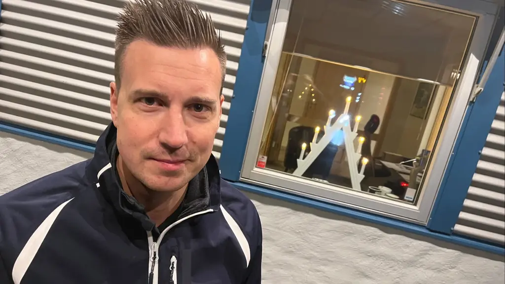 Fredrik Johansson står framför en byggnad med ett stort glasfönster där en adventsljusstake syns. Han bär en mörk jacka med vita detaljer. 