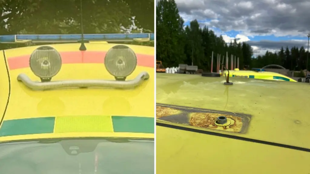 Närbild på taket av en gul ambulans där blåljusrampen saknas; bara fästen och kablar syns. I bakgrunden väg och skog i Värmland.