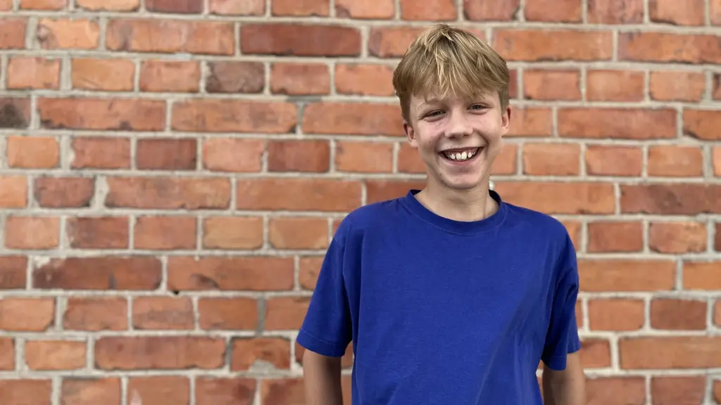Harald Fohlin, 13 år, från Bysarnas speedwayklubb står framför en tegelvägg. Han är klädd i en blå t-shirt och ska tävla i ungdoms-VM i Speedway mot världseliten.