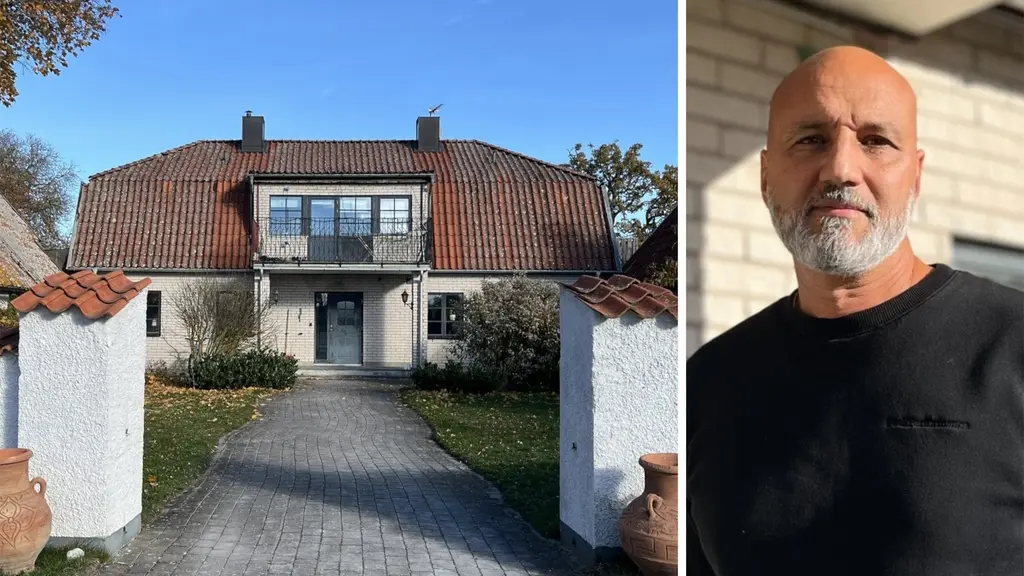 Ett vitt hus med rött tegeltak bakom en mur och en man i svart tröja