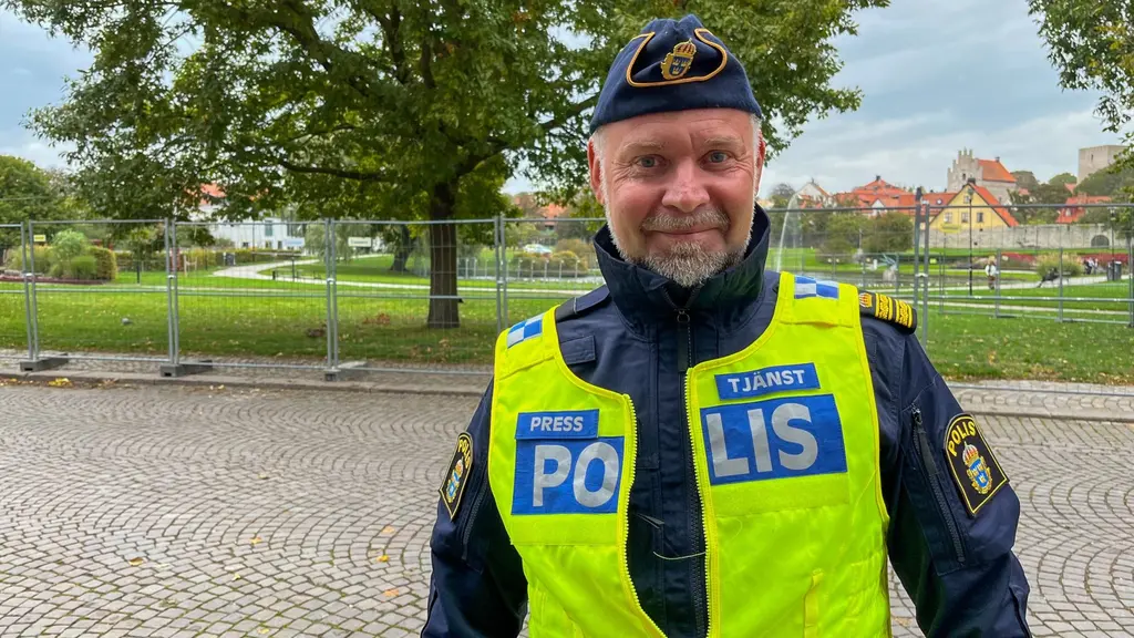 En polis i gul reflexväst står framför avspärrningar i Almedalen i Visby.