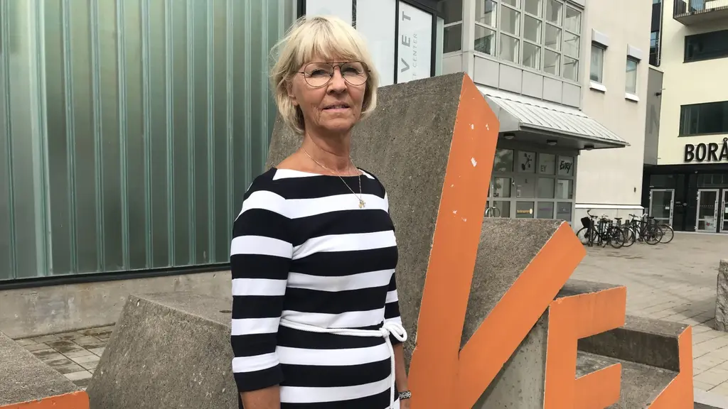 En kvinna i randig klänning står framför Navets skylt.