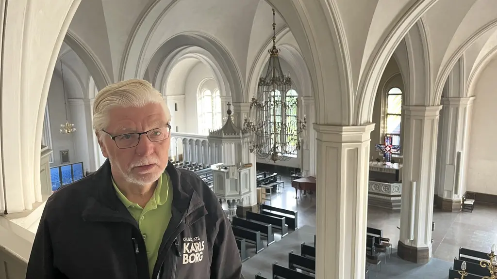 Guiden Sture Karlsson står i en kyrka med höga valv, pelare och bänkrader. Interiören domineras av ljus stenarkitektur och ett stort kyrkorum i bakgrunden.