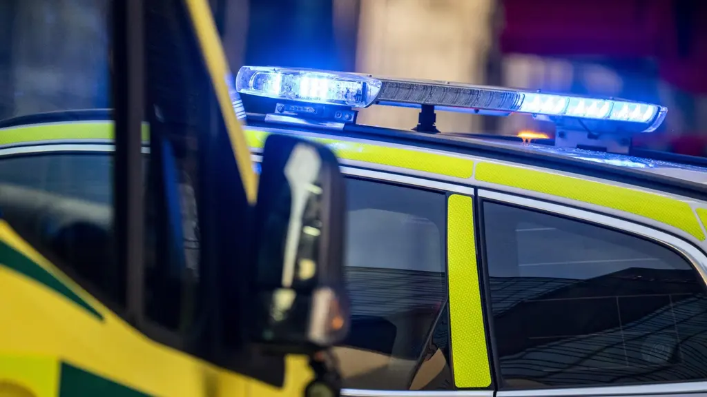 Polisbil och ambulans. Polisen har blinkande sirener.