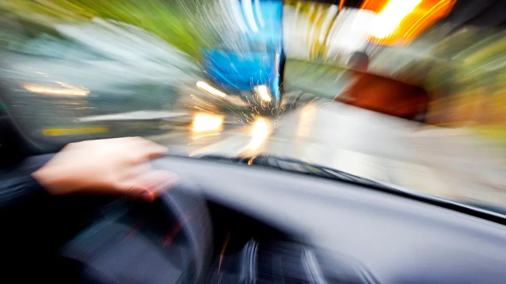 En suddig bild av en hand på en ratt i en bil som är ute och åker.