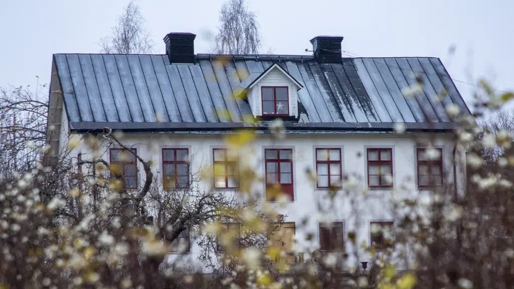 På bilden syns en stor vit villa med röda fönster. 