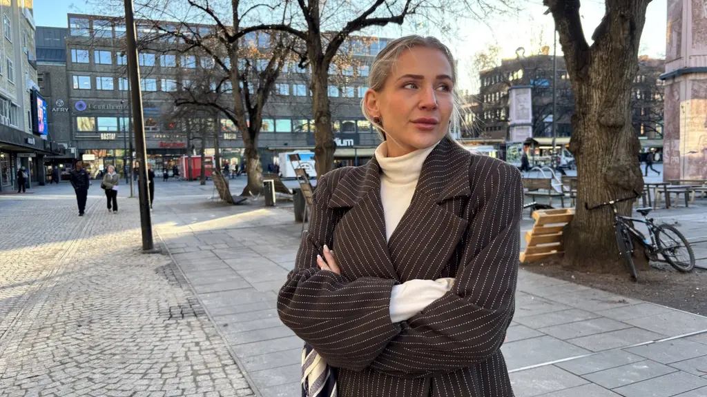 En kvinna står på torget i Gävle, i bakgrunden syns personer som går och affärer. 