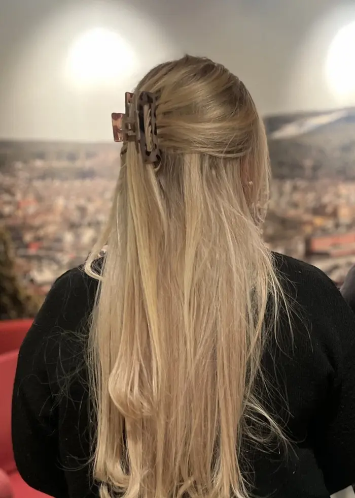 Två kvinnliga kriminalvårdare står med ryggen mot kameran i ett rum med röda soffor och en väggmålning av ett stadsmotiv. En lampa lyser svagt och växter syns i bakgrunden.