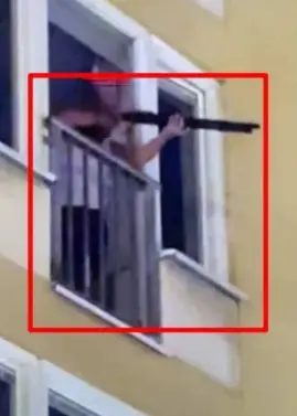 En person står på en balkong i en gul byggnad och håller i ett långt föremål som liknar ett gevär. Två bilder visas bredvid varandra med röda markeringsrutor kring personen.