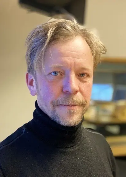 Porträttbild allvarlig man med blont hår och svart tröja i radiostudio