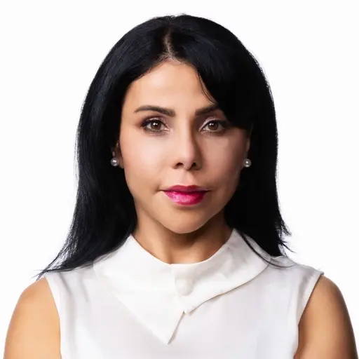 En kvinna med långt hår bär en vit topp med hög krage. Bakgrunden är vit.