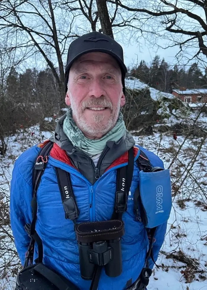 Till vänster syns Niklas Holmström klädd i blå jacka, mössa och kikare utomhus i ett snötäckt skogsområde. Till höger ligger en person i en sovsäck på marken i en solig skogsbacke.