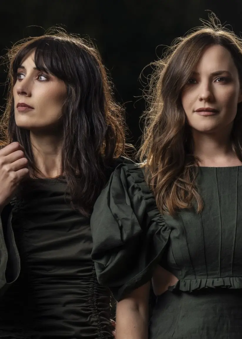 Två kvinnor i svart med mörk bakgrund. Foto: Pressfoto