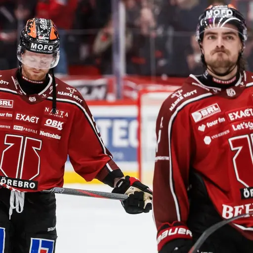 En ishockeyspelare från Örebro med nummer 77 på tröjan ser nedstämd ut efter en match i SHL. Han står på isen med klubban i handen, omgiven av rödklädda lagkamrater och publik i bakgrunden.