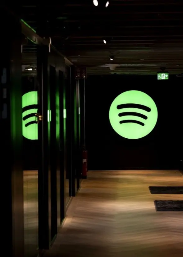 Spotifys logotyp mot en mörk bakgrund i en mörk korridor