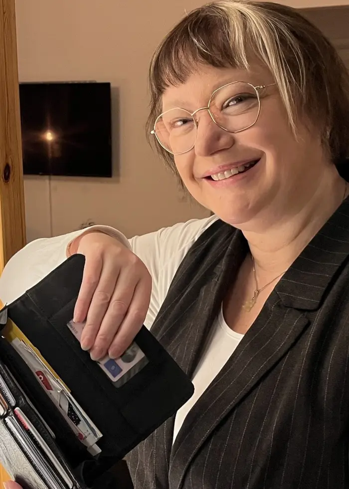 Camilla Olsson står i lägenhetsmiljö och håller upp den plånbok som varit försvunnen i 14 år.