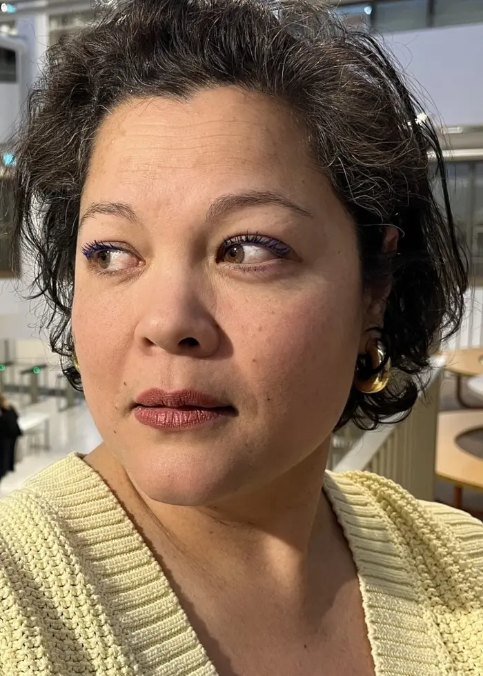 En ljus och modern byggnad med flera våningar, öppna ytor och glasdetaljer. Personer rör sig i bakgrunden, och rummet är inrett med bord och stolar. Arkitekturen har en minimalistisk stil.