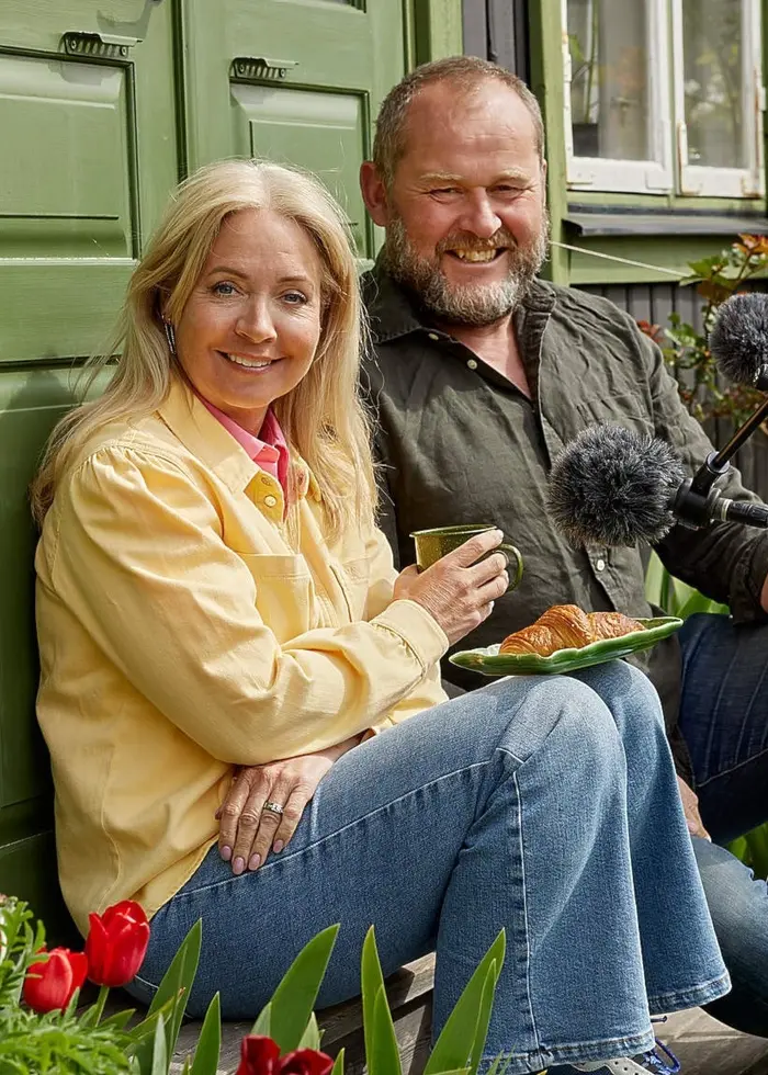 Pernilla och John sitter på trappan till Johns kolonistuga