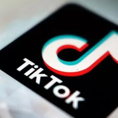 En ung tjej dricker mjölk och har på sig ett halsband som liknar en nazistsymbol. Texten på bilden lyder: 'The larp has taken to the streets.' Bredvid syns TikToks logotyp på en skärm. 