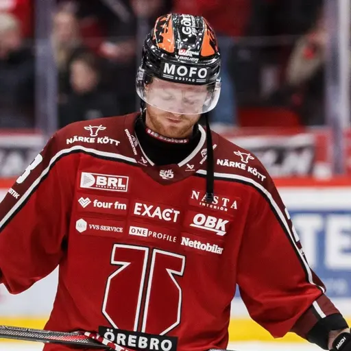 En ishockeyspelare från Örebro med nummer 77 på tröjan ser nedstämd ut efter en match i SHL. Han står på isen med klubban i handen, omgiven av rödklädda lagkamrater och publik i bakgrunden.