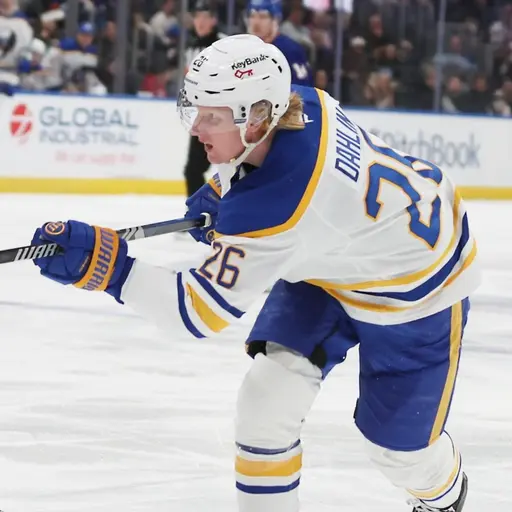 Två hockeyspelare på isen. En med vit tröja och en med blå tröja. Den med vit tröja tar ett avslut.