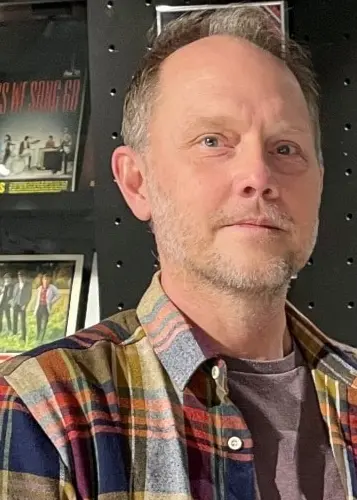 En man står med LP-skivor från ABBA i bakgrunden.