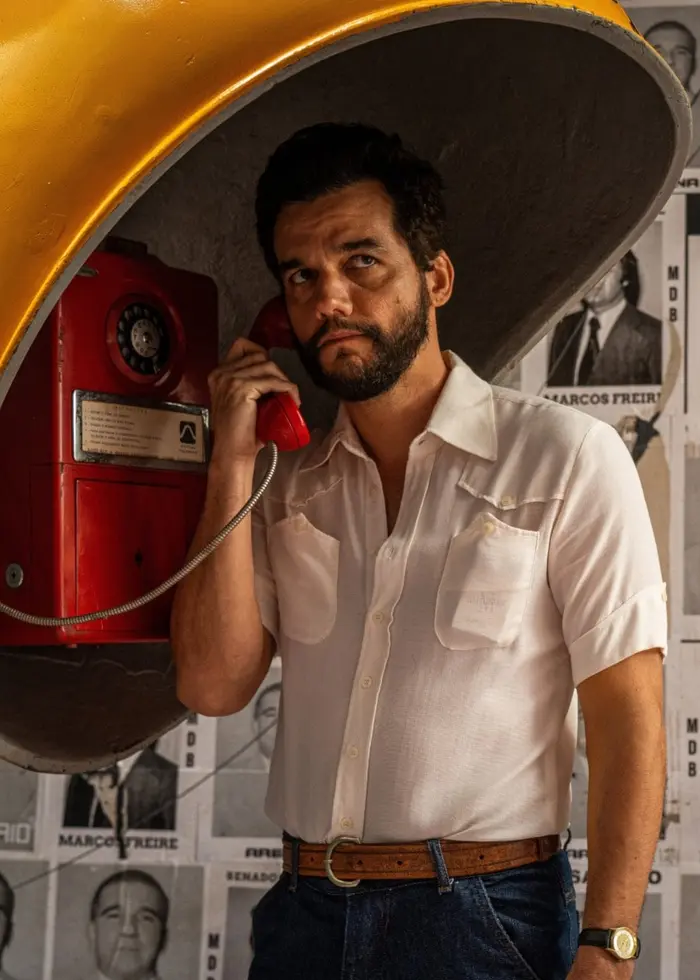 Wagner Moura i huvudrollen i filmen ”The Secret Agent”, står vid en telefonautomat med ett kupolliknande gult tak.