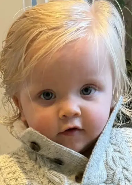 En blond pojke i stickad vit tröja.