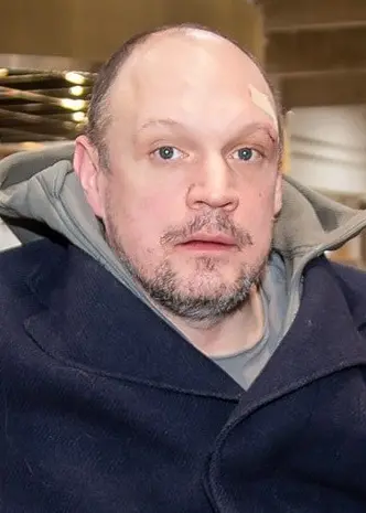 Jonatan Unge sitter i en gul soffa. Han har på sig en blå rock.