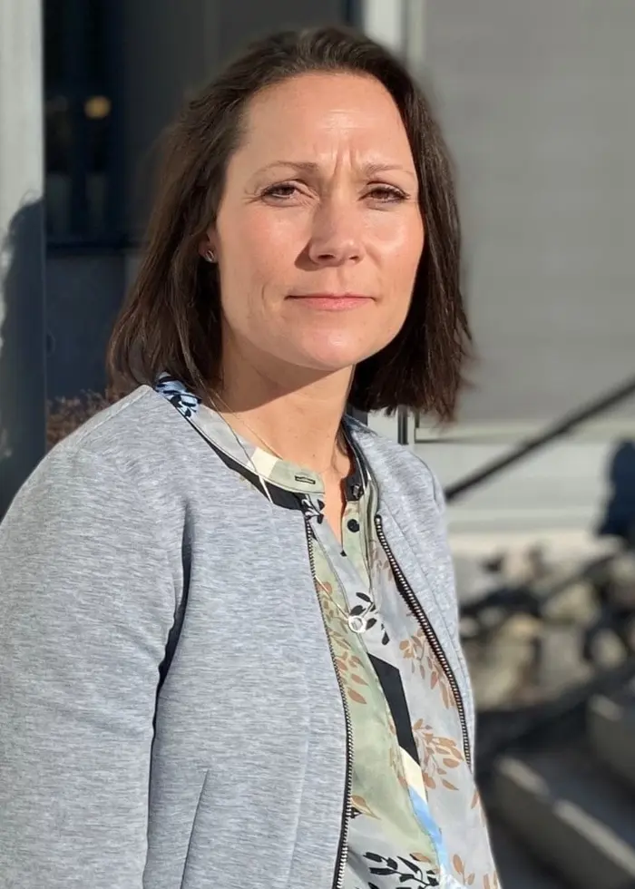 Malin Eriksson framför länsstyrelsens skylt, hon har grå tröja på sig.