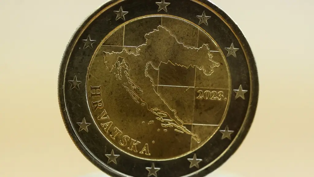 En närbild på ett mynt som visar en karta över Kroatien, placerat ovanpå flera andra mynt. Bilden symboliserar Kroatiens övergång till euron som valuta och landets ekonomiska integration i EU.