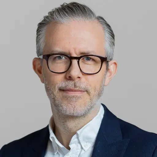 Landskapsbild över Rapadalen med slingrande floder och frodig grönska omgiven av berg. Till höger en person i kostym fotograferad mot grå bakgrund.