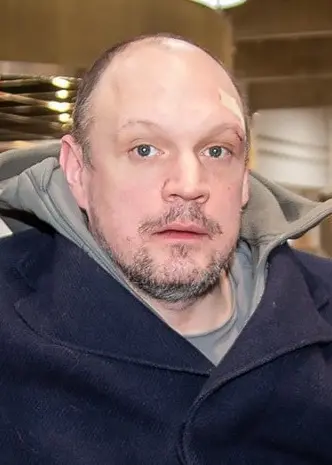 Jonatan Unge sitter i en gul soffa. Han har på sig en blå rock. 