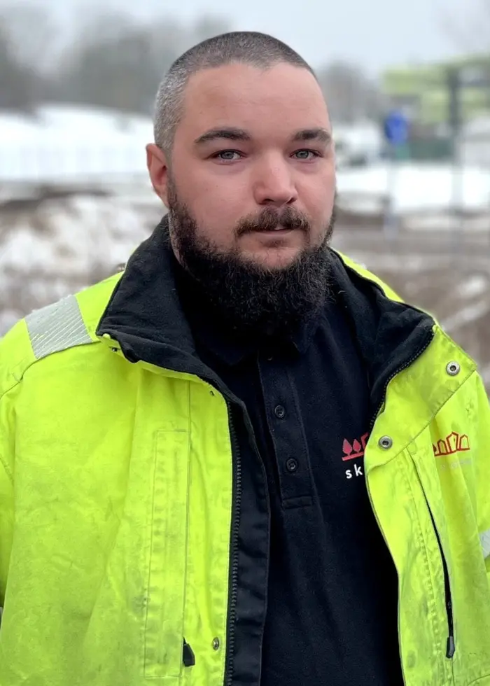 En man med gulgrön arbetsjacka och en man med grön jacka och röd mössa.