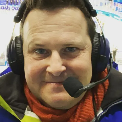 Två personer iklädda vinterkläder syns i bild. Den vänstra personen bär en mössa med text och glasögon, medan den högra personen har på sig hörlurar och en vinterjacka.