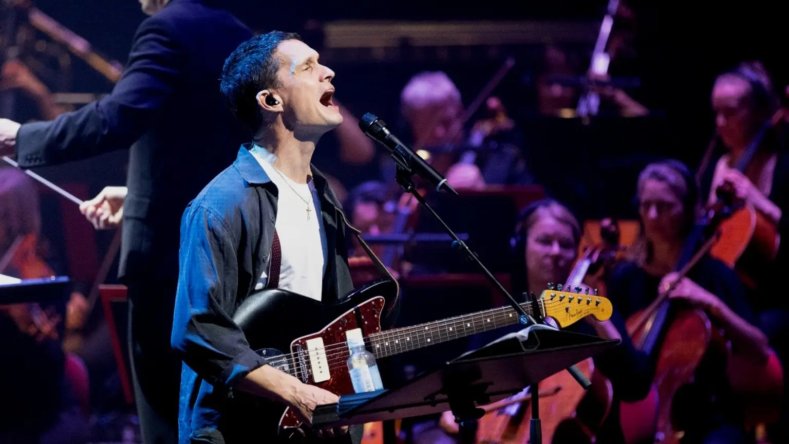 Jonathan Johansson, med elgitarren på magen, sjunger framför Sveriges Radios Symfoniorkester och dirigent Erik Arvinder.