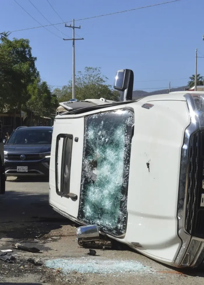 Militärfordon patrullerar förbi ett omkullvält och förstört fordon på en gata i Jesus Maria, Mexiko. Situationen är spänd efter en operation mot en högprofilerad narkotikahandlare.