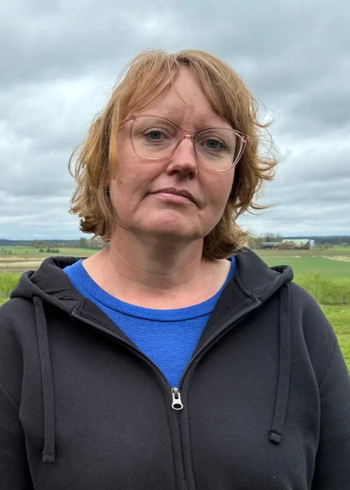 Två personer utomhus på landsbygd i Götene, fotograferade från bröstet upp under molnig himmel, i nyhetsbild om kritik mot kommunen efter A-traktorolycka.