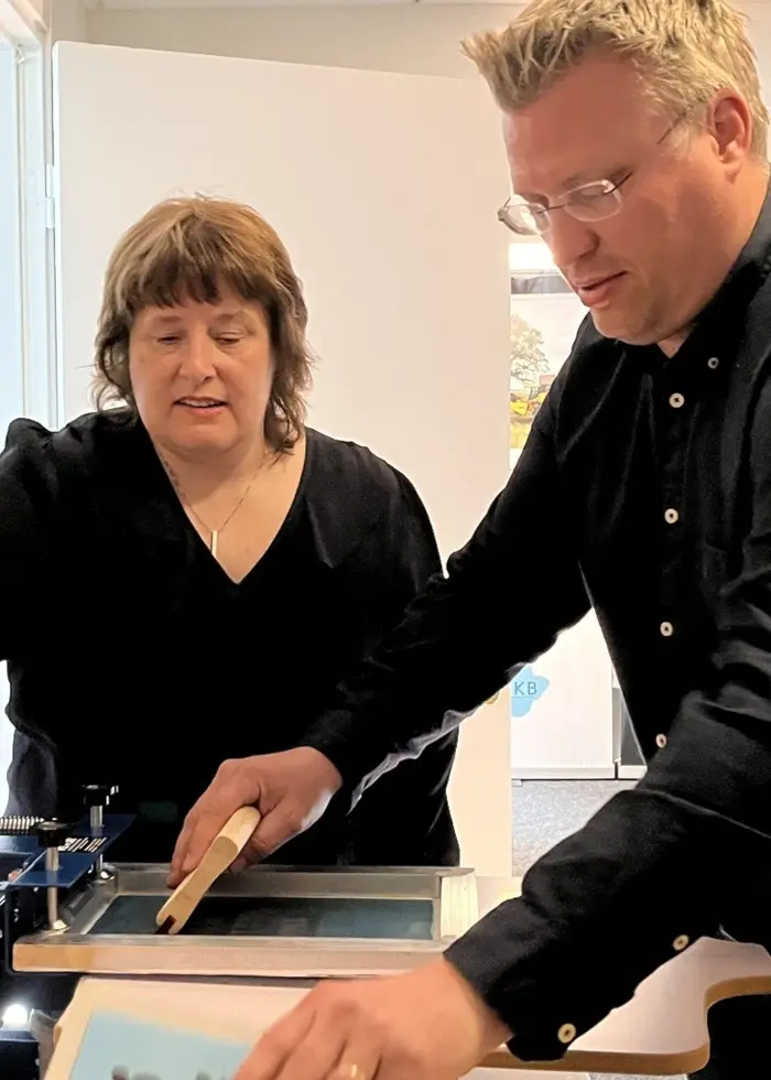 Carl Hellqvist och Susanne Lundgren trycker disktrasor vid en arbetsstation inomhus i Vara, i en bild om lokal produktion och arbete.
